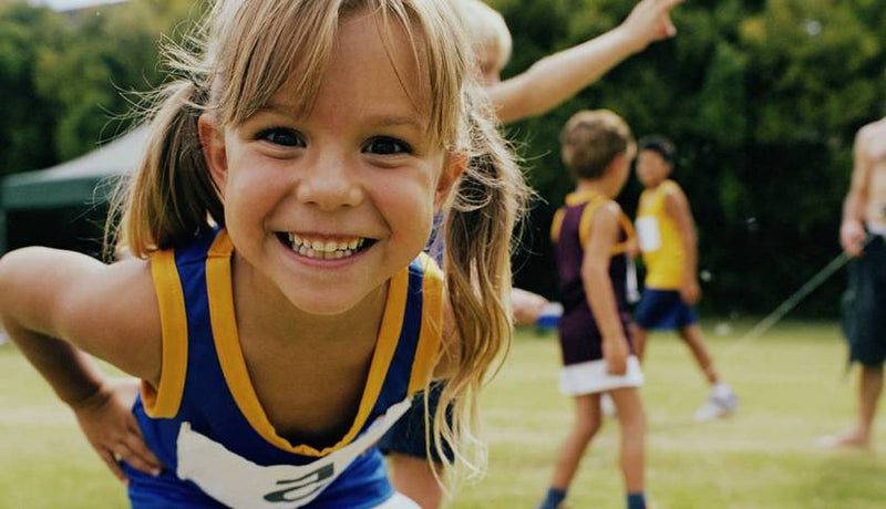 Petite fille souriante en tenue de sport sur un terrain, prête pour son activité physique